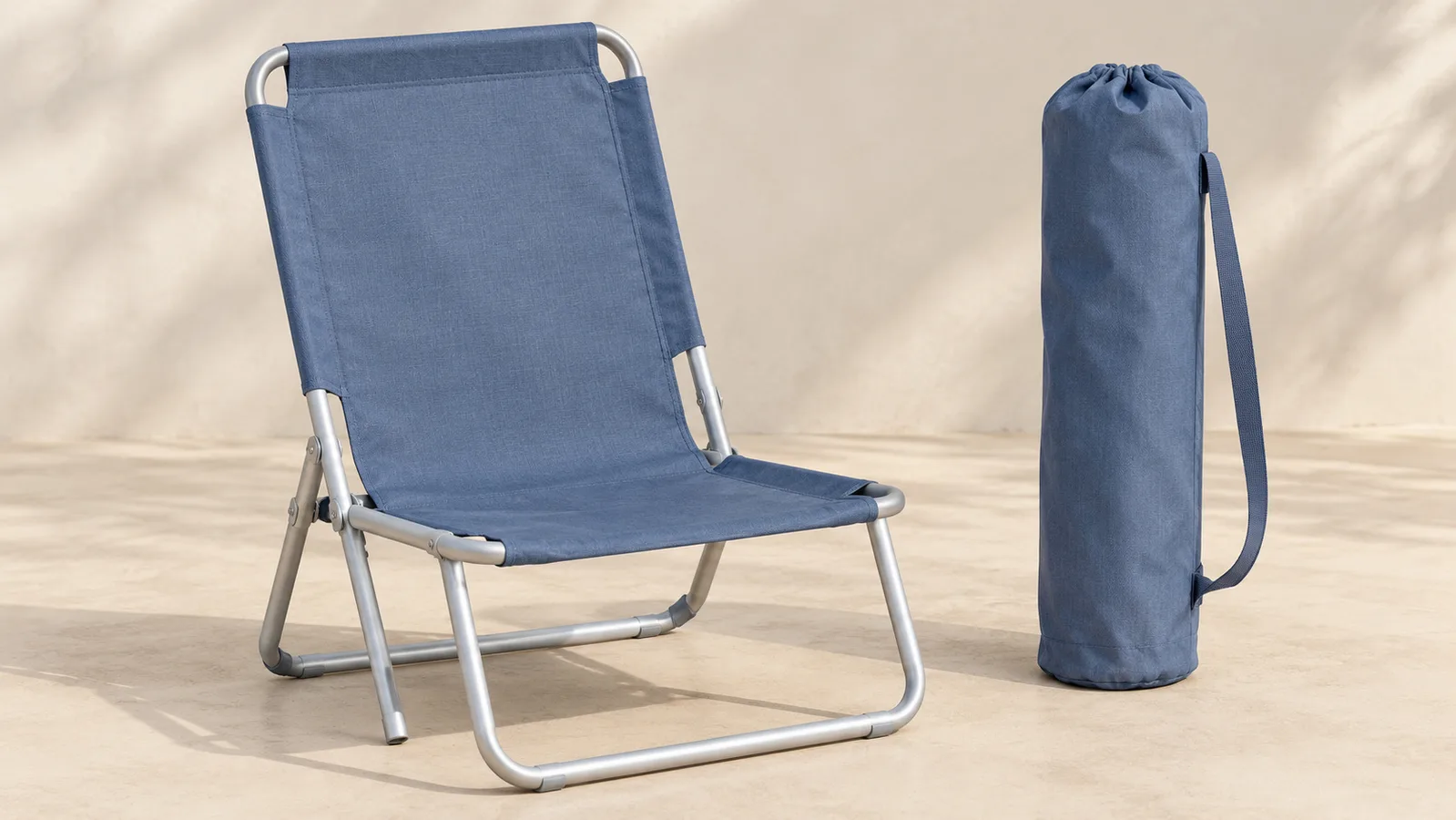 Una semplice sedia da spiaggia pieghevole mostrata aperta accanto alla sua borsa per il trasporto abbinata